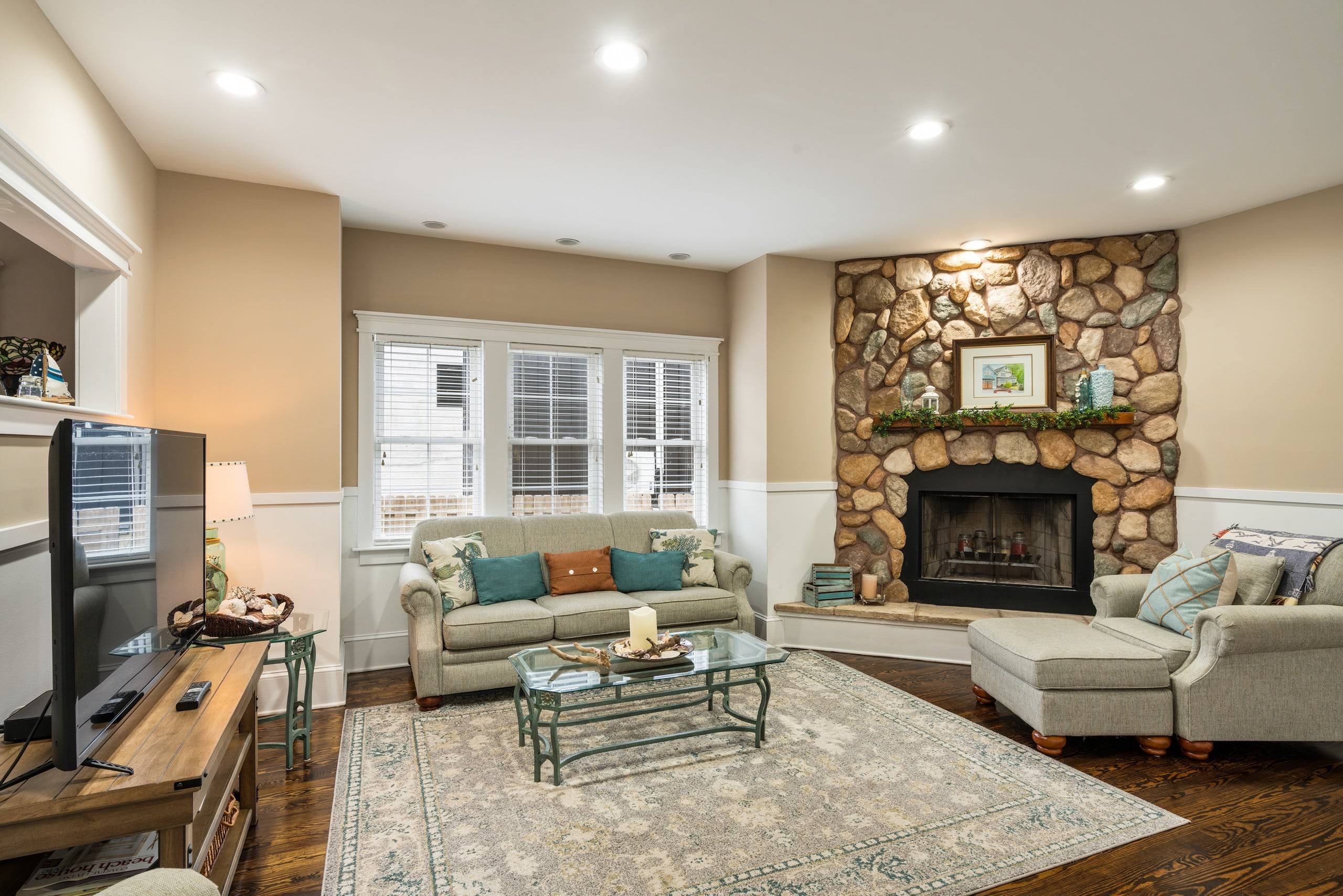 Living room at Fern with a stone fireplace and windows
