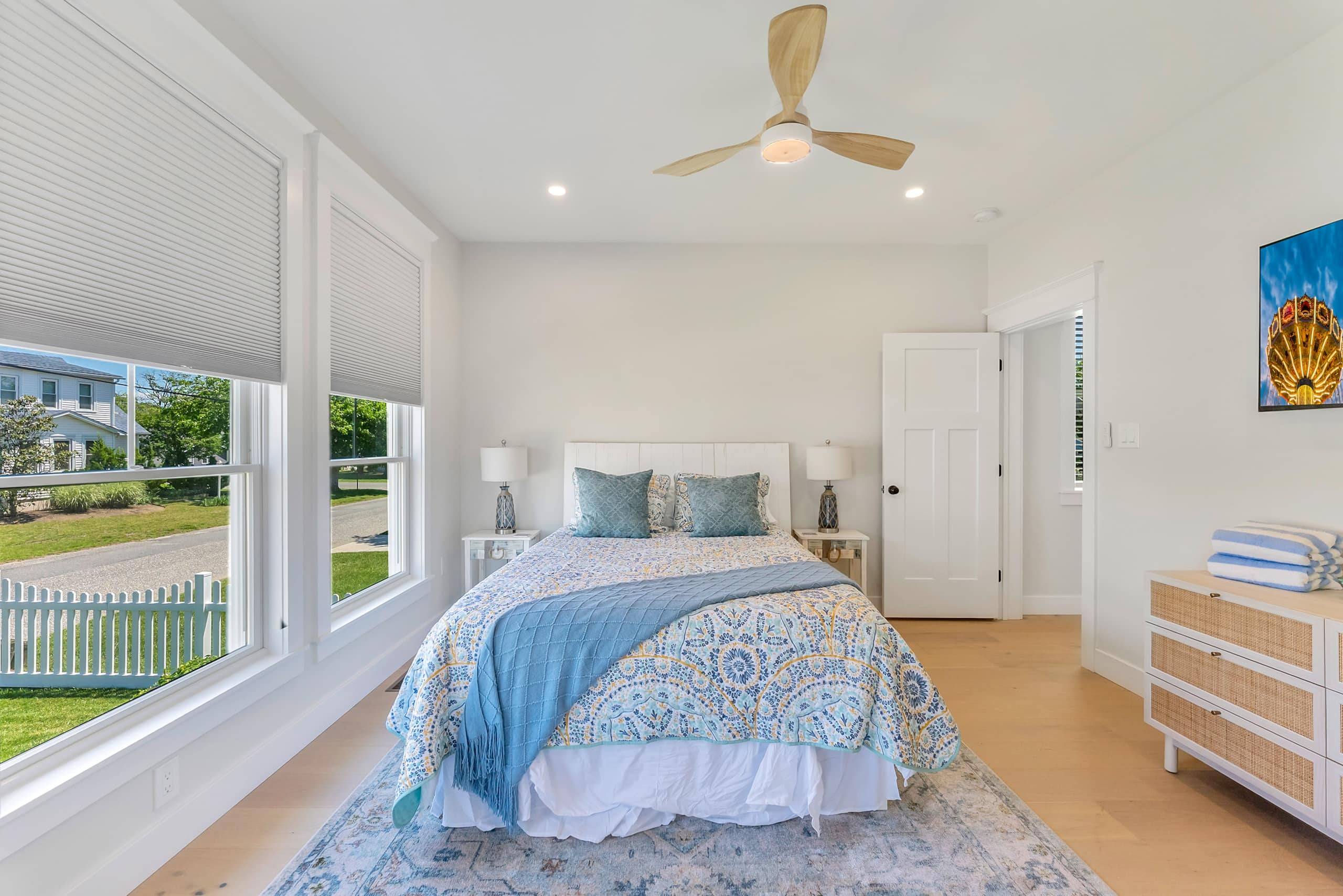 Bedroom at The Delford with a blue quilt and a window toward the water