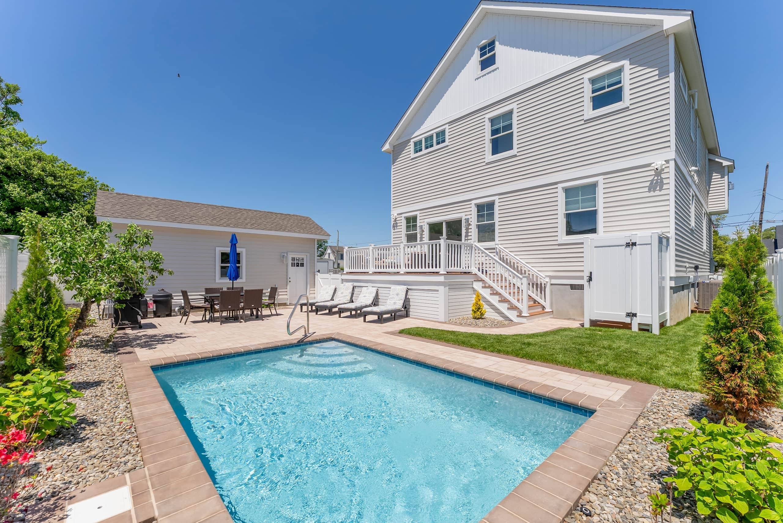 Heated pool, lounge chairs, and outdoor dining in the fenced yard at The Delford